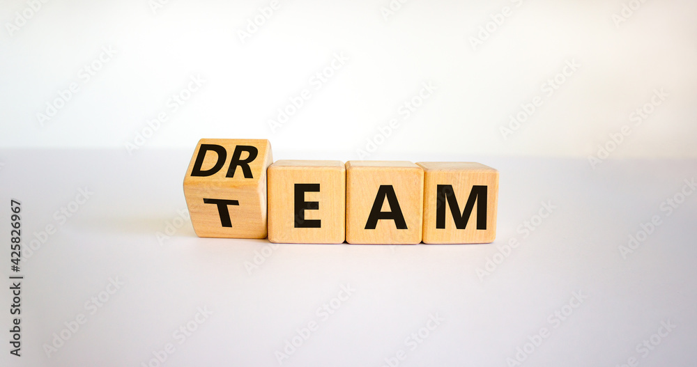Dream team symbol. Turned the cube and changed the word 'dream' to 'team'. Beautiful white table, white background. Business and dream team concept, copy space. Dream team symbol. Turned the cube and changed the word 'dream' to 'team'. Beautiful white table, white background. Business and dream team concept, copy space.