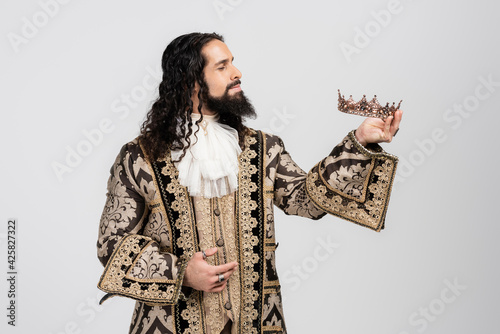 hispanic king in medieval clothing holding golden crown isolated on white