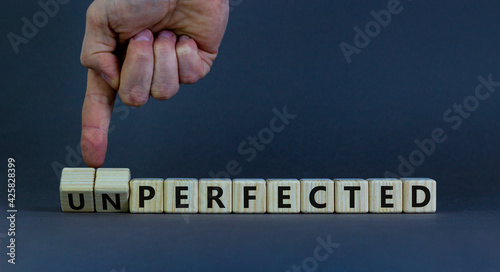 Perfected or unperfected symbol. Businessman turns wooden cubes and changes the word unperfected to perfected on a beautiful grey background. Business, perfected or unperfected concept. Copy space.