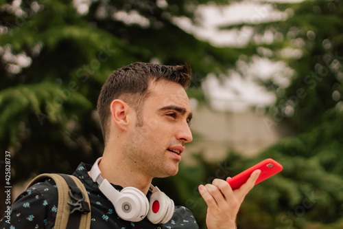 Foto A young Hispanic man talking on his smartphone, on a street outdoors