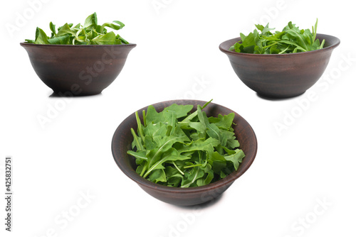 Fresh leaves of arugula in ceramic brown bowl isolated.