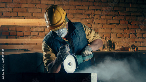 Male builder in respirator cutting wall photo