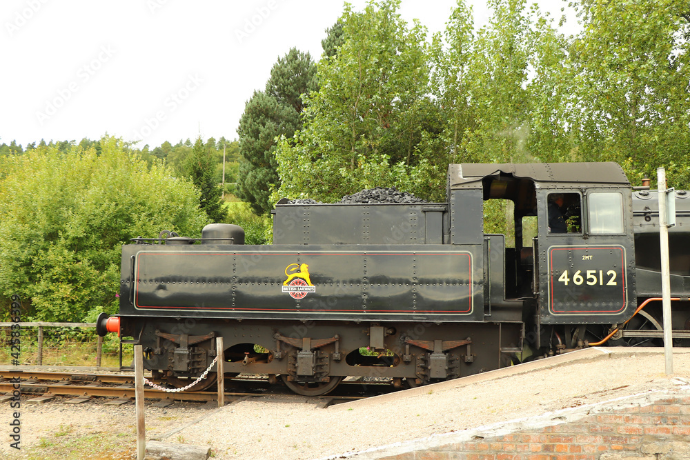 Fototapeta premium Steam locomotive full of coal running on a track through the countryside 