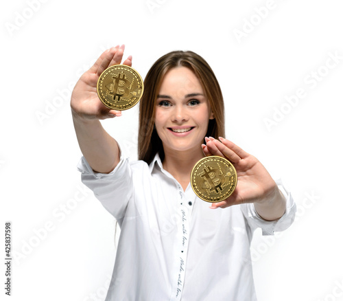 Bitcoin coins in the hands of a smiling young woman. Mining and cryptocurrency concept