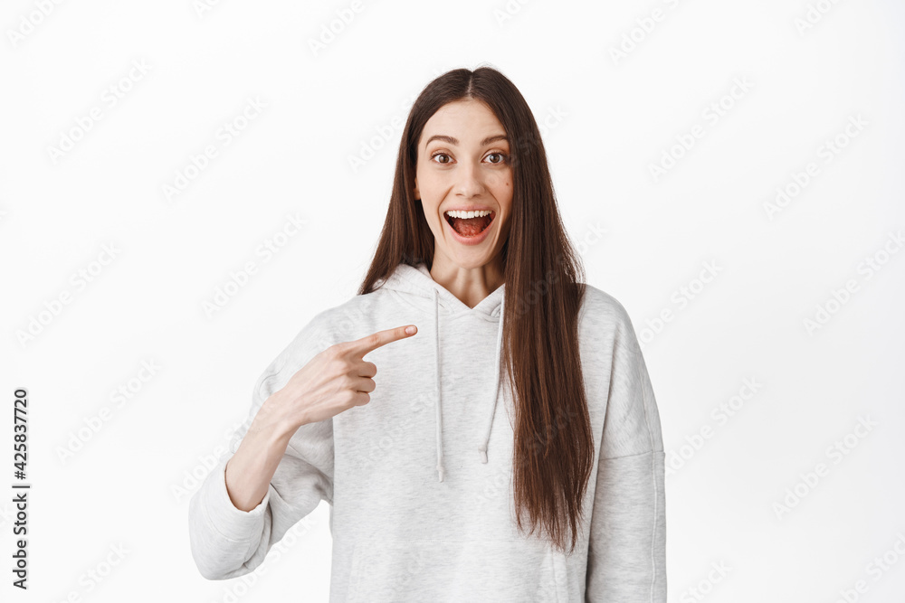 Surprised girl student pointing at herself and smiling amazed, being chosen, winning trip or prize, stare with amazement and disbelief at camera, become winner, white background Surprised girl student pointing at herself and smiling amazed, being chosen, winning trip or prize, stare with amazement and disbelief at camera, become winner, white background