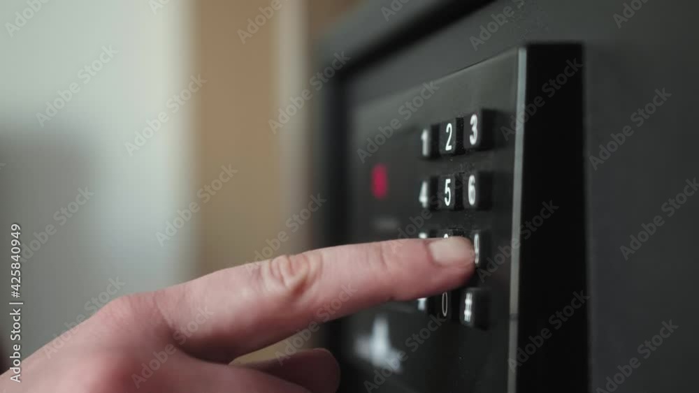Close-up of hand opening metal safe box with pass code in the hotel room.