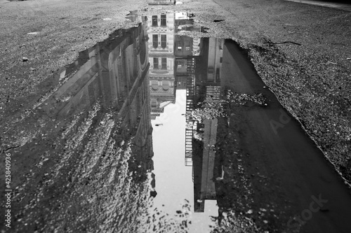 buildings reflected in water on pavement 