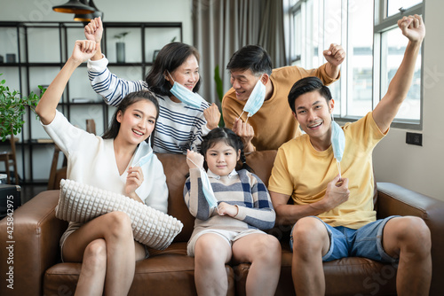 social distancing and new normal concept.strong healthy asian family wearing surgical protective face mask stay quarantined together at home.