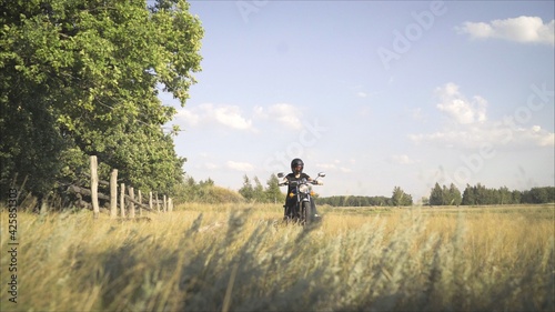 Motorcyclist rides on the field. The concept of adventure. Motorcyclist rides on a country road in the summer.