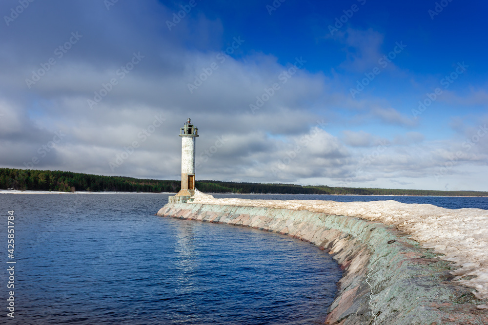 Obraz premium A lighthouse in sunny weather. Lighthouse on the breakwater. Lighthouse on the lake.