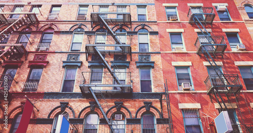 Retro toned picture of old brick buildings with fire escapes, New York City, USA.