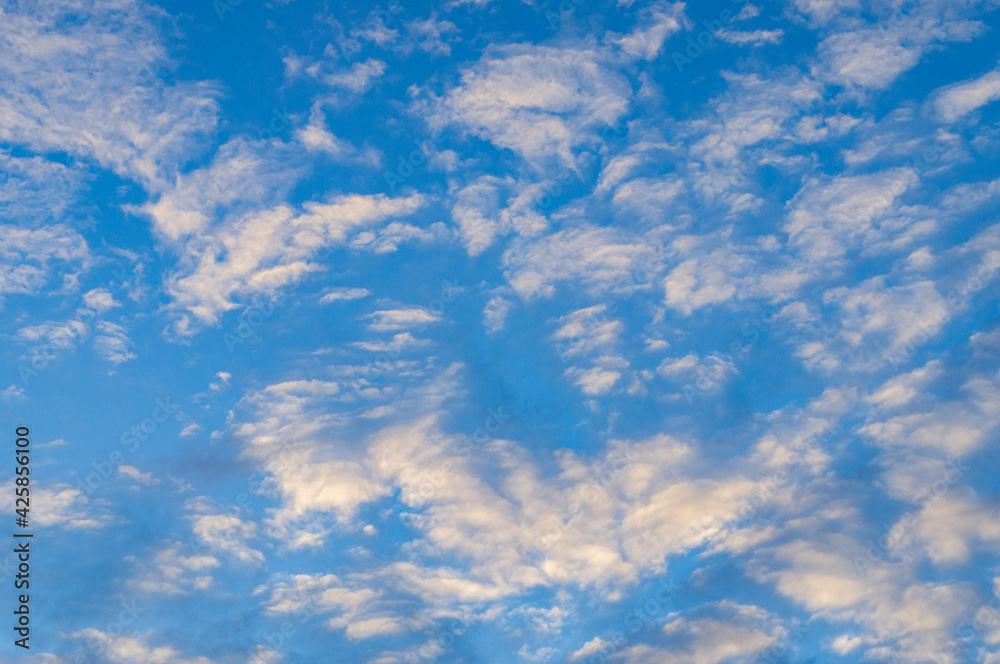 Blue sunny sky with white contrasting clouds for background