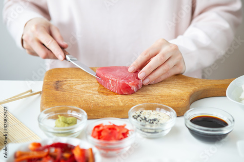 The process of preparing sushi, preparing all the ingredients for sushi, the girl cuts the tuna.