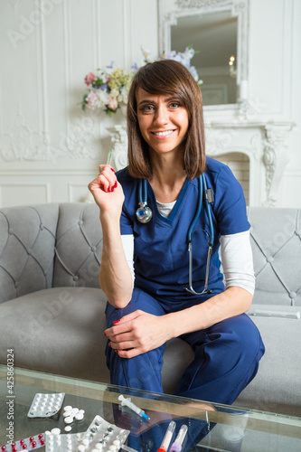 joyful physician is sitting on a sofa with mercury thermometer in her hand photo