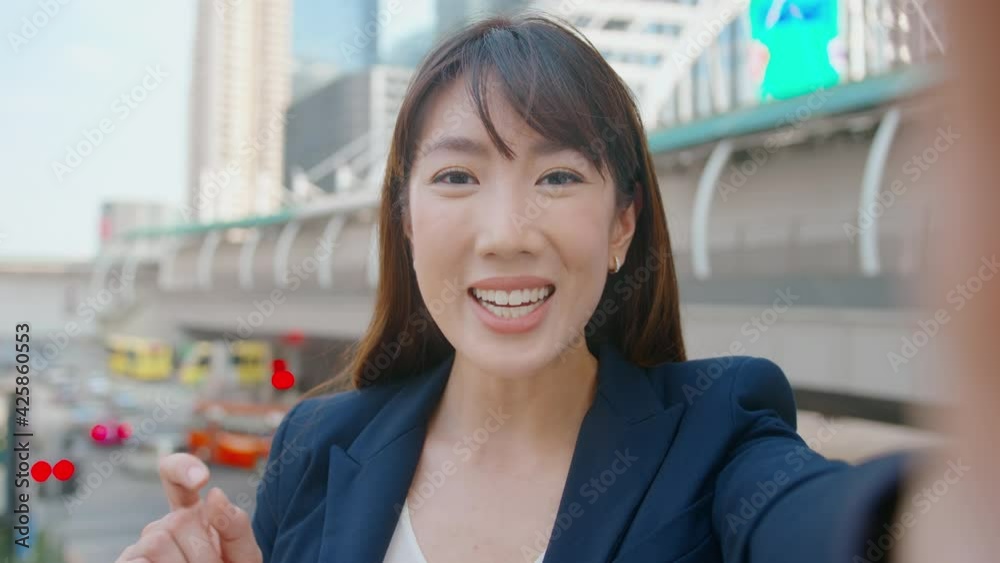 An asian beautiful business woman is making video call with colleagues or family in modern city , business cooperation and business technology concept.