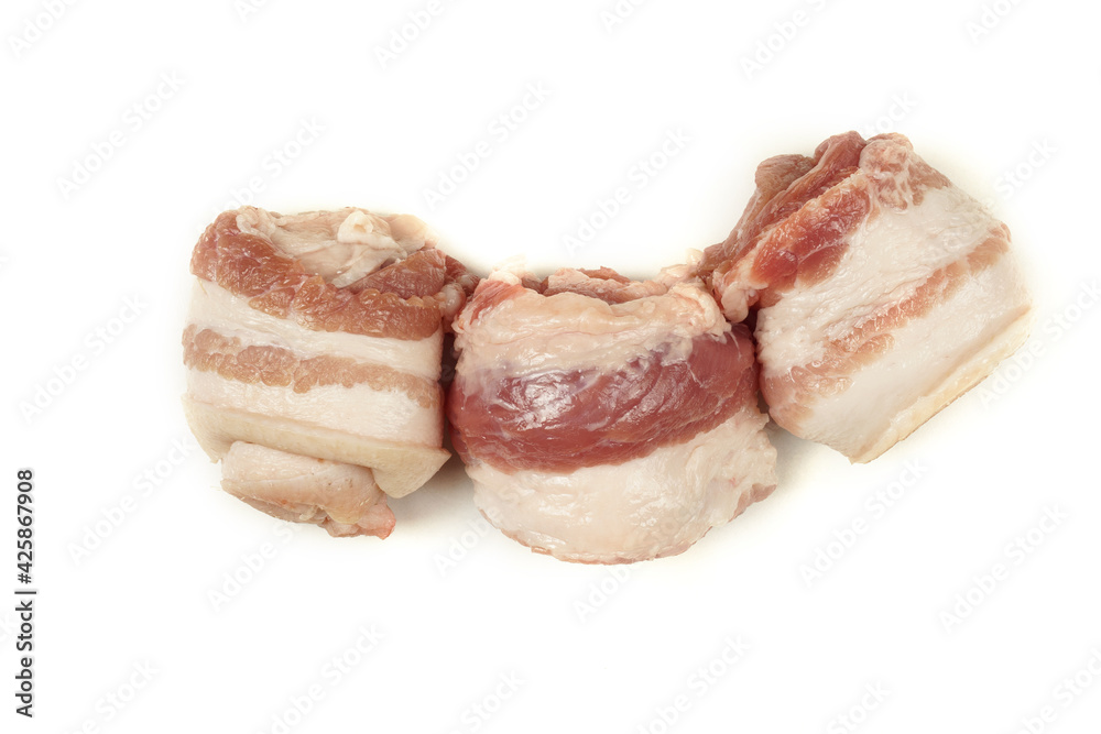 Three raw bacon rolls rolled into a tube. Raw meat with lard. Isolated