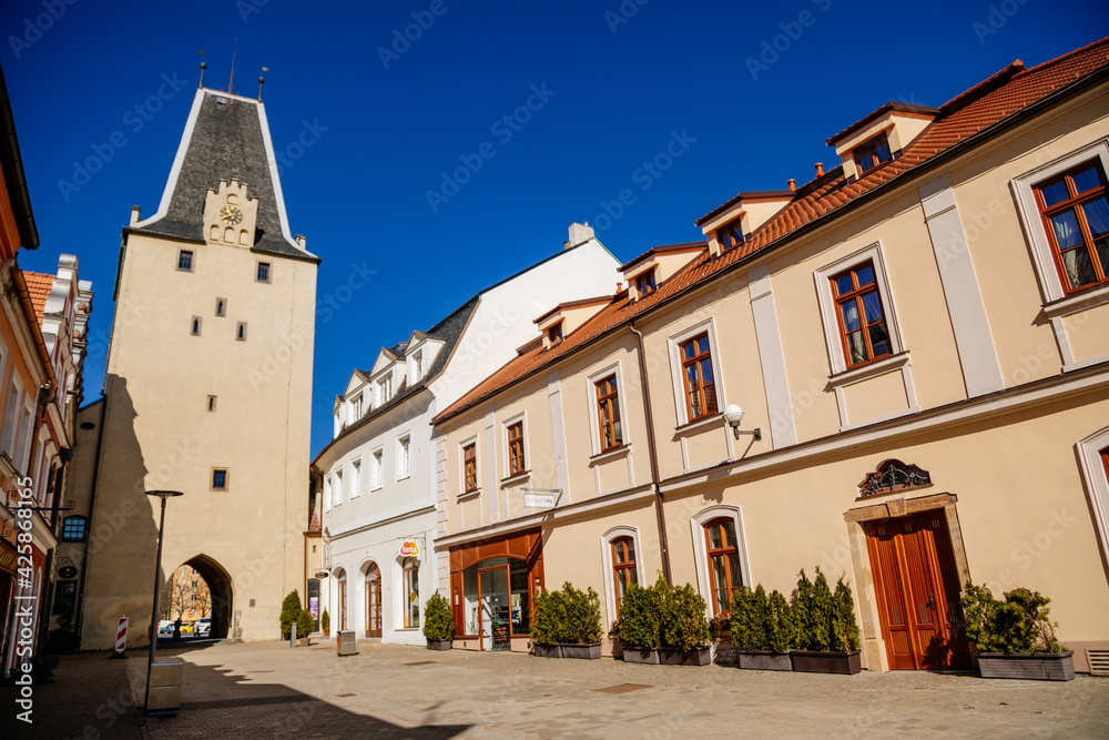 Gothic clock tower Mikulov Gate, Narrow picturesque street with colorful renaissance and baroque buildings in historic center in medieval town, sunny day, Kadan, Czech Republic Gothic clock tower Mikulov Gate, Narrow picturesque street with colorful renaissance and baroque buildings in historic center in medieval town, sunny day, Kadan, Czech Republic