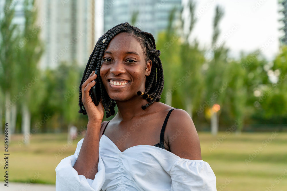 Beautiful young black girl talking on the phone in a park