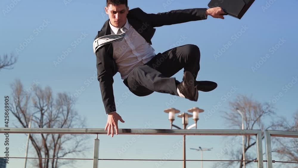 Businessman in a jacket and tie with a suitcase in his hands jumps over