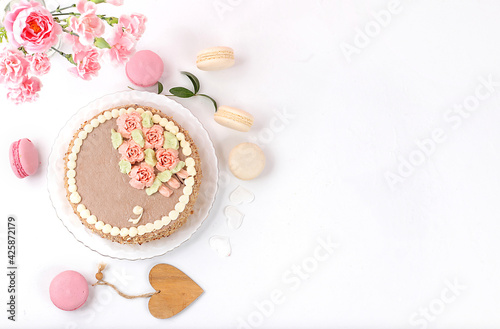 Cake with chocolate and meringue, marshmallows and flowers on a light table, festive food for mother's day, wedding, birthday. Modern bakery concept, selective focus, delicious dessert. 