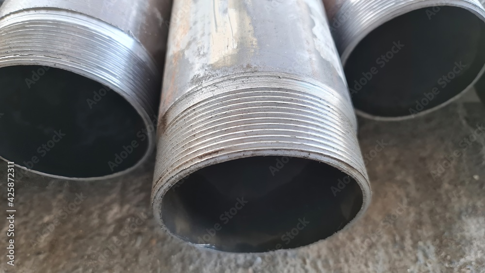 Stack of oil production pipe that store at material yard. Normally pipe threaded. Selected focus on threaded each. Close up object. Stack of oil production pipe that store at material yard. Normally pipe threaded. Selected focus on threaded each. Close up object.