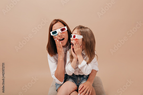  Close up portrait of pretty woman with dark hair wearing movie glasses watching movie with her little adorable girl