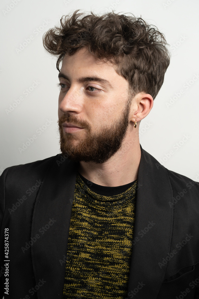Fototapeta premium Portrait of a bearded young guy on a white wall moth a new haircut.