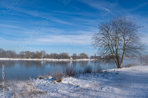 beautiful frozen river called werdersee at sunny warm white winter day with snowy dike and cloudy sky in bremen © Danny