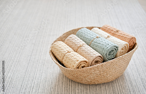 Collection of natural muslin bath towels in a wicker basket on the floor. Natural, soft, air and stylish home textiles. View from above.