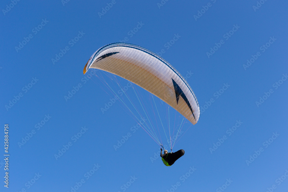 A paraglide flying gliding on a clear blue sky at the golden hour with a nice wind windy breeze on a sunny day A paraglide flying gliding on a clear blue sky at the golden hour with a nice wind windy breeze on a sunny day