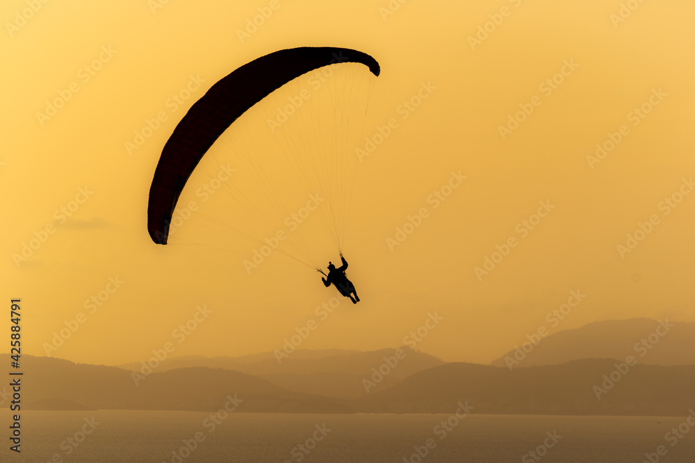 A paraglide flying gliding on a clear blue sky at the golden hour with a nice wind windy breeze on a sunny day A paraglide flying gliding on a clear blue sky at the golden hour with a nice wind windy breeze on a sunny day
