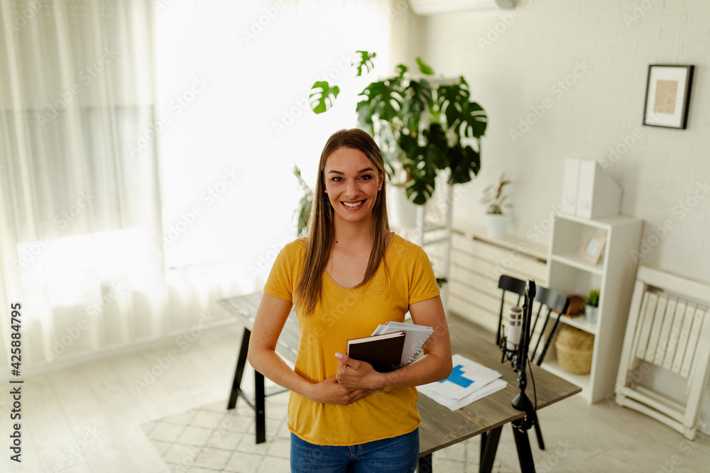 Portrait of a beautiful designer, standing and looking at camera while she is holding a notes. Portrait of a beautiful designer, standing and looking at camera while she is holding a notes.