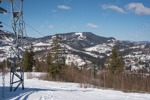 Ski chair lift. Snow-capped mountain peaks on a winter sunny day. Carpathians. Ukraine. The outskirts of the village of Slavsko.
