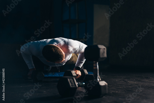Man doing pushups with dumbbells in the gym