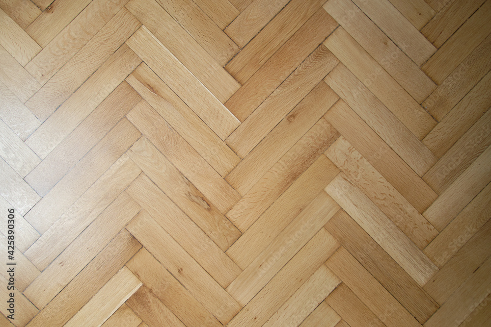 Classic old wooden parquet laying in the form of a herringbone in light brown color. Imeless classics in the design of the floor in the house.