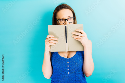 Beautiful young woman portrait covering her face looking to the side at the good side. reading concept shyness concept photo