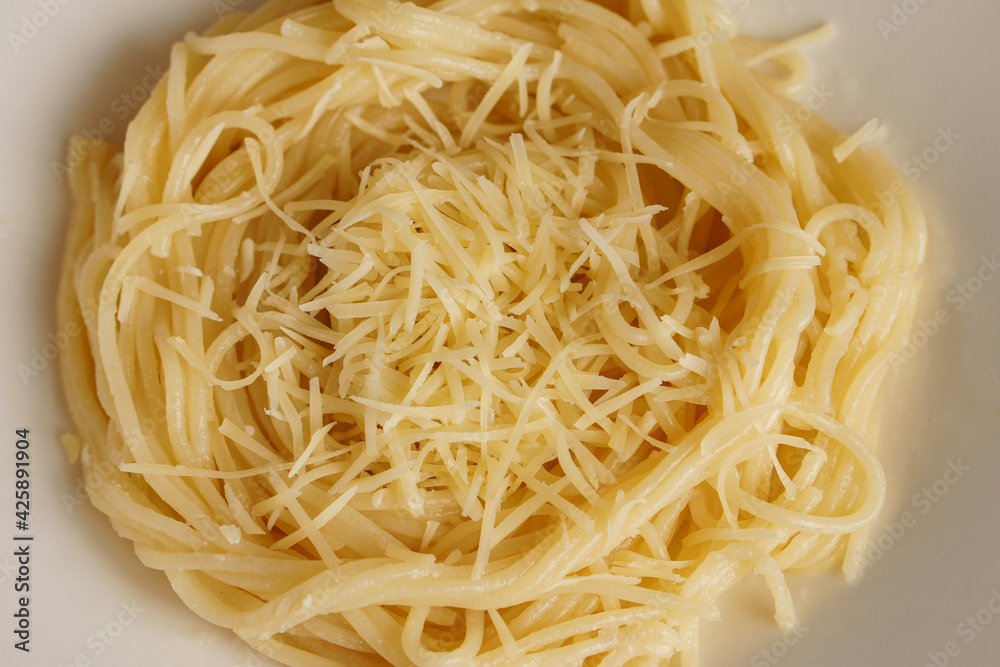Hot pasta is sprinkled with grated cheese