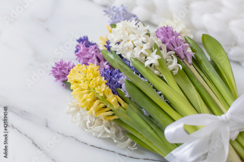 Bouquet of spring colored flowers of hyacinths. White marble background and fluffy knitted plaid