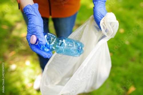 Fotografie Volunteer picking up the plastic garbage and putting it in biodegradable trash-bag on outdoors