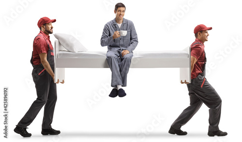 Movers carrying a single bed with man in pajamas and a cup of tea photo