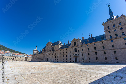 El Escorial, Spain- March 17, 2021: Monastery of El Escorial. Facade with parade ground and gardens of the Escorial Monastery. Spanish Royal Palace. National Heritage. Culture of the Spanish royalty. photo