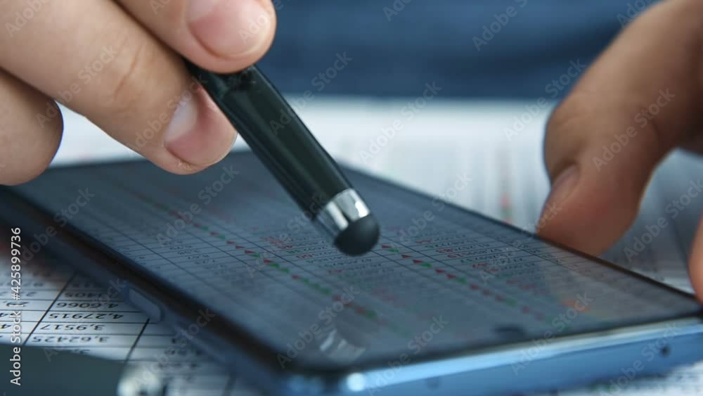 Businessman With Stylus In Hand Monitoring Statistic On Mobile Phone Screen. Internet Trading And Stock Statistics Concept. Slow Motion Effect. Close Up Businessman With Stylus In Hand Monitoring Statistic On Mobile Phone Screen. Internet Trading And Stock Statistics Concept. Slow Motion Effect. Close Up