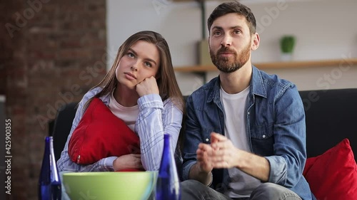 a woman is bored while her partner is watching sports on TV. The man rejoices in the success national team, hugs the girl, drinks beer.