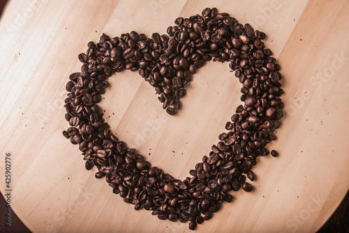 Coffee beans in a heart shape on a wooden board. Top view.