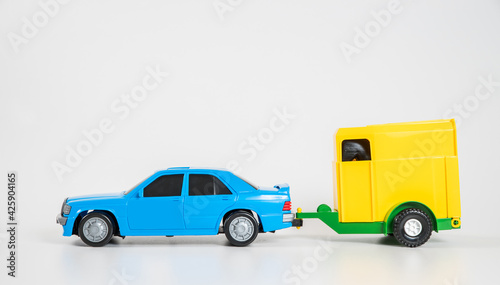 Children's toy plastic car isolated on white background. A multicolored passenger car with a horse trailer.