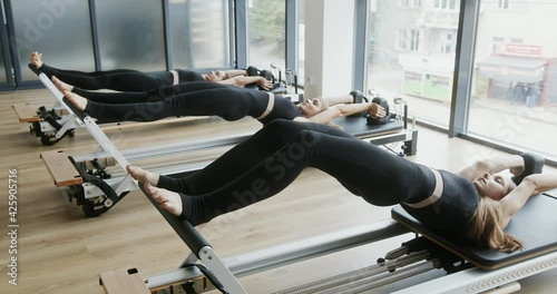 Three athletic women working out on pilates reformers photo