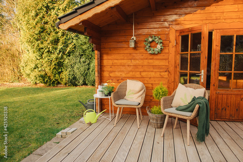 Woven garden chairs stand in front of a wooden garden shed. Nice garden furniture in spring. Enjoy the weather outside in spring 