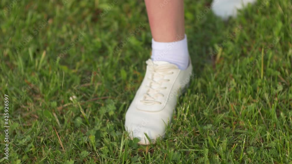 Walking girl in white sneakers on the green grass. Walking girl in white sneakers on the green grass.
