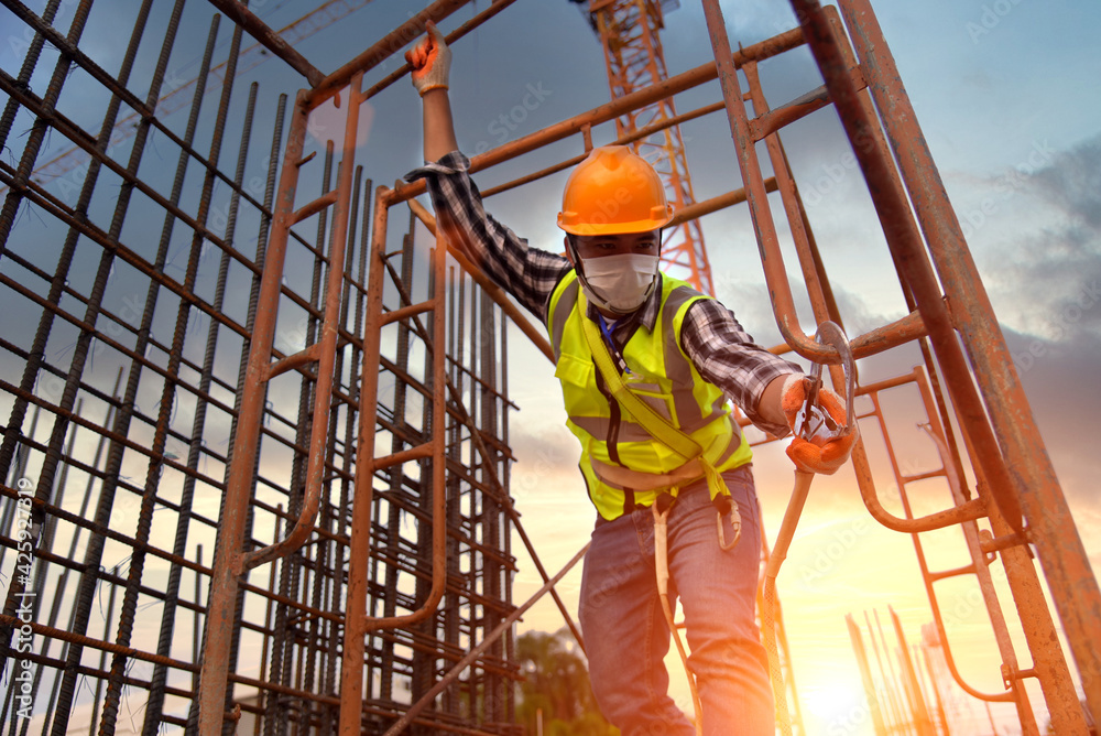 Construction workers hook up safety belts At construction working