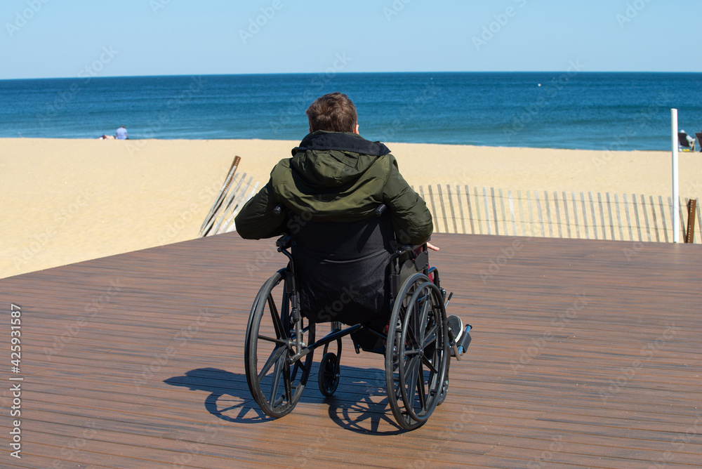 Man sitting in a wheelchair on the beach wheel medical